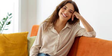 woman sitting on her couch trying to attract money and wealth