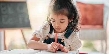 little girl struggling to hold a pencil