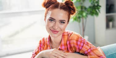 young middle class woman smiling sitting on inexpensive furniture
