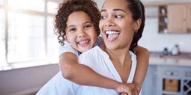 mom giving daughter piggyback at home