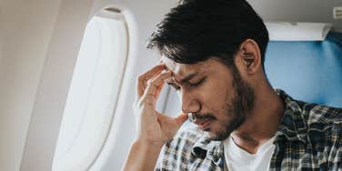 Man looks stressed on plane.
