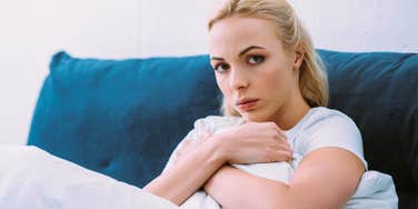 broke woman sitting on couch looking stressed