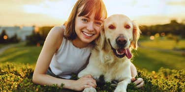 smiling woman and her happy dog in a field