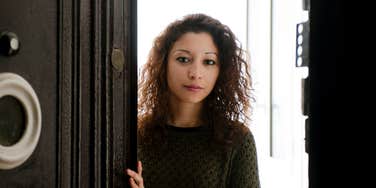 frugal woman opening door to rich persons home looking judgmental