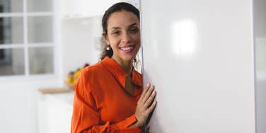 frugal woman standing in front of open freezer door