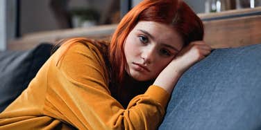 young woman emotionally checked out of her social life alone at home
