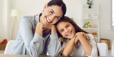 smiling teacher sitting next to happy student