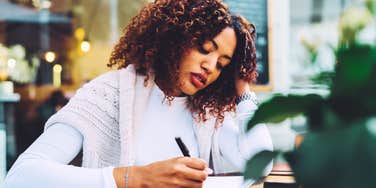 Woman writing in physical planner. 