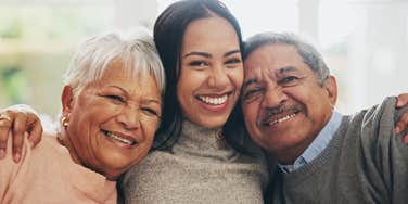 adult woman in between her loving parents hugging and smiling