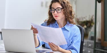 woman examining financial documents while online banking