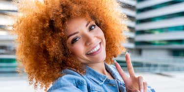 woman smiling give peace sign looking happier than everyone else
