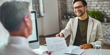 job seeker handing hiring manager resume during interview