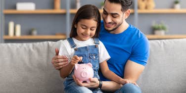 dad and daughter putting money in piggybank