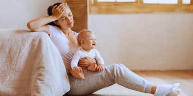 stressed out mom holding baby sitting on floor