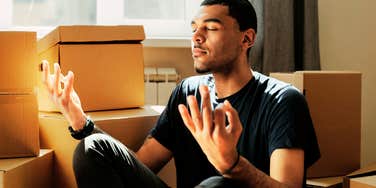 Man meditating quickly while unpacking. 