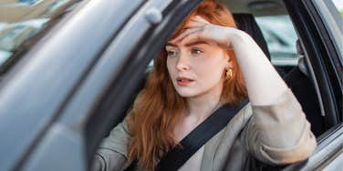 sad stressed woman sitting in car behind steering wheel