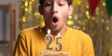 man blowing out the candles on a birthday cake