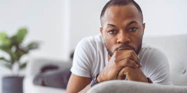 extremely unhappy man sitting on his couch moping