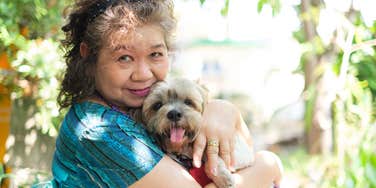older woman snuggling her dog outside