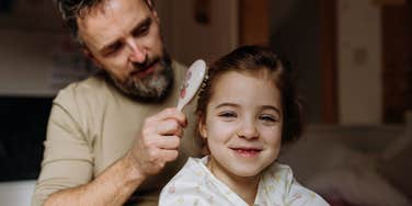 single dad brushing his daughter's hair
