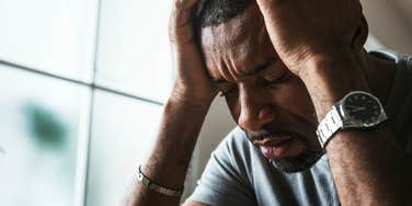 upset man holding his head in his hands