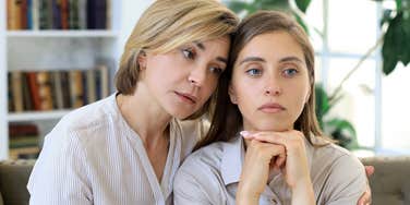 middle aged mom comforting adult daughter who's hiding something from her