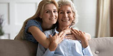adult woman hugging her mother from behind smiling