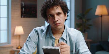 man with a notepad looking judgmental