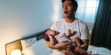 overwhelmed husband holding newborn baby