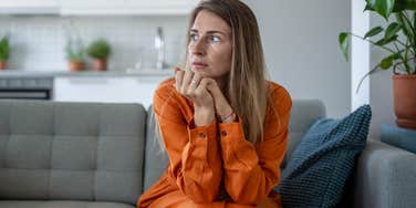 concerned woman looking around friend's house sitting on couch