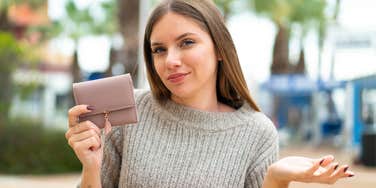 cheap woman holding wallet not wanting to spend money