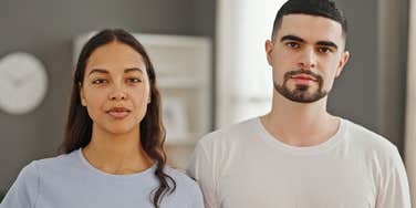narcissistic woman standing next to husband looking calculated
