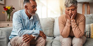 upset wife sitting beside husband during conflict