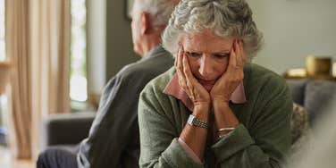 upset older woman sitting with back turned to husband