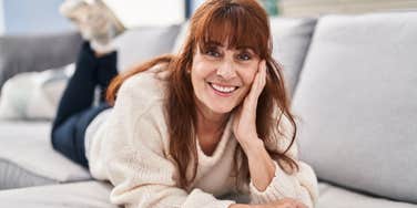 older woman smiling relaxing at home laying on the couch