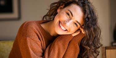 Smiling young woman relaxing at home, illustrating the beautiful secrets of people who are joyfully single and whole