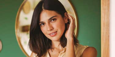 Smiling woman in sleeveless shirt touching her hair, embodying the warmth and beauty of soulful, deep love