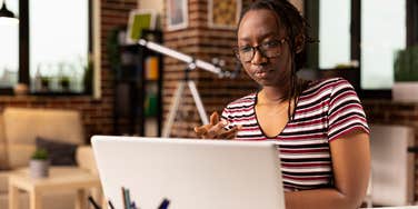 focused black woman speaking with team during virtual meeting on laptop