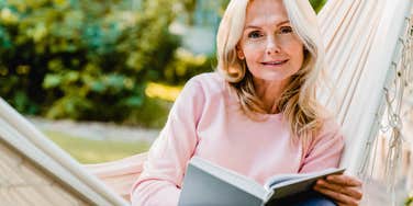 trustworthy woman reading a book in a hammock