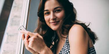 defiant millennial woman smiling on her phone