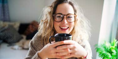 Happy woman holding coffee, illustrating daily habits that help people age slower and live happier, healthier lives