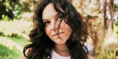 Woman with long hair in a park, pondering if she truly loves him or is just emotionally attached