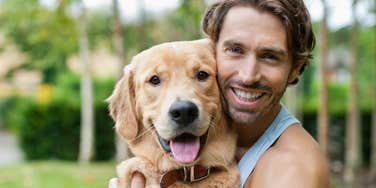 man smiling sitting next to his very happy dog