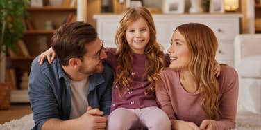 loving parents sitting on the floor with child teaching them lessons