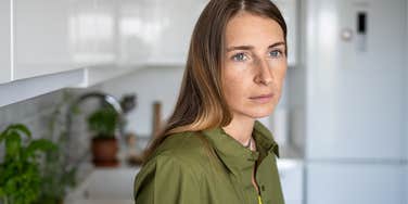 woman standing in her kitchen thinking about her struggling finances
