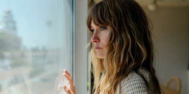 woman looking out the window craving connection but needing alone time
