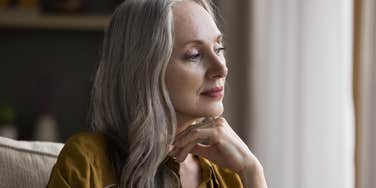 woman reminiscing while looking out window at home