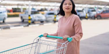 woman pushing shopping cart in parking lot