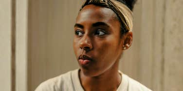 Woman with stoic expression looking off to the side, illustrating signs you’re always playing therapist to someone who won’t change.