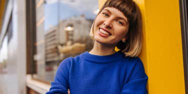 high value woman in blue standing outside smiling